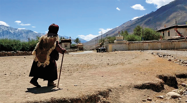A village woman of Zanskar dressed in traditional clothes. She is walking towards the Sani Monastery A village woman of Zanskar dressed in traditional clothes. She is walking towards the Sani Monastery