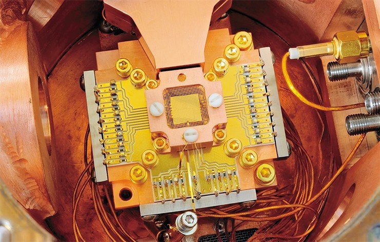 Ученые из Национального института стандартов и технологии США (NIST) разработали специальную ловушку, в которой удерживается два иона бериллия, находящиеся на расстоянии 40 мкм друг от друга. Ионы располагаются над золотой пластинкой, окруженной для уменьшения электростатических помех золотой сеткой и медным корпусом. Credit: Y. Colombe/NIST