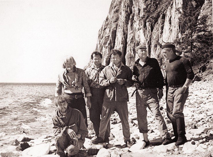 1974 г. Славное море – Священный Байкал. Бухта Саган-Заба, скала с древними рисунками. Слева направо стоят: водитель А. И. Логинов, аспирант Ю. П. Холюшкин, кинооператор студии ЗапСибКинохроника В. И. Пономарев, академик А. П. Окладников, начальник отряда м.н.с. И. В. Асеев, сидит старший лаборант В. П. Мыльников