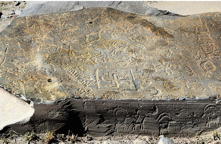 A large flat stone slab, which lies at the entrance to the new rock art site near the village of Akshow, shows images of the various Buddhist symbols. The slab lies flat; it is completely covered with engravings, but the images can be barely seen on the surface, as if obliterated by time. The slab awaits a more detailed study, but it has already been found to contain images of flowers, branches, swastikas, solar symbols, and tower-shaped stupas. Even its end part is covered with much better preserved images of the ibex. Zanskar, 2019 A large flat stone slab, which lies at the entrance to the new rock art site near the village of Akshow, shows images of the various Buddhist symbols. The slab lies flat; it is completely covered with engravings, but the images can be barely seen on the surface, as if obliterated by time. The slab awaits a more detailed study, but it has already been found to contain images of flowers, branches, swastikas, solar symbols, and tower-shaped stupas. Even its end part is covered with much better preserved images of the ibex. Zanskar, 2019